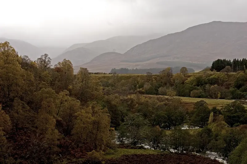 Misty river valley in the Scottish Highlands surrounded by autumn trees