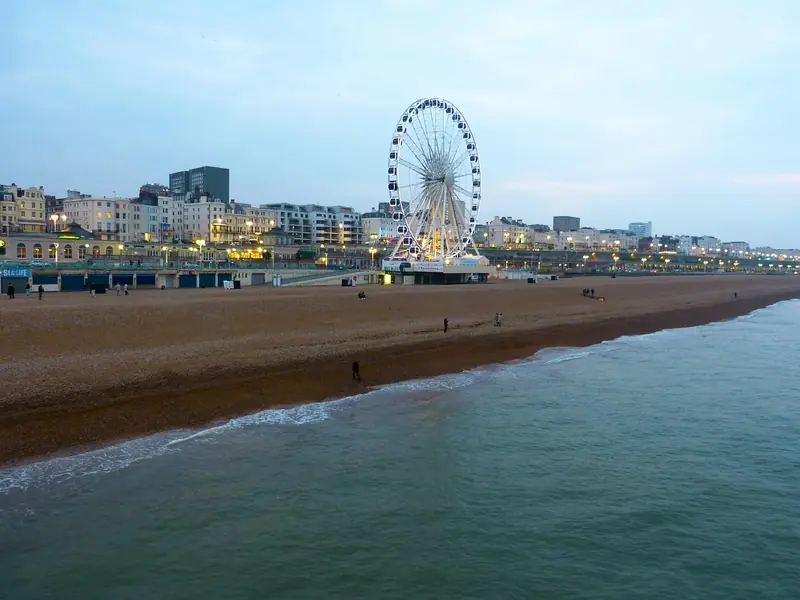 Brighton's pebble beach and illuminated pier wheel at dusk