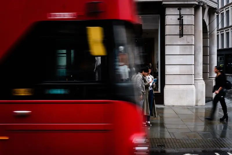 Iconic red double-decker bus passing pedestrians on a London street