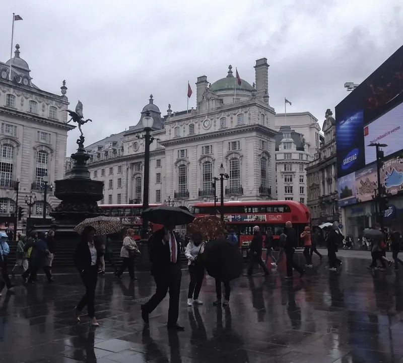 Piccadilly Circus in the rain with pedestrians and a red bus, London