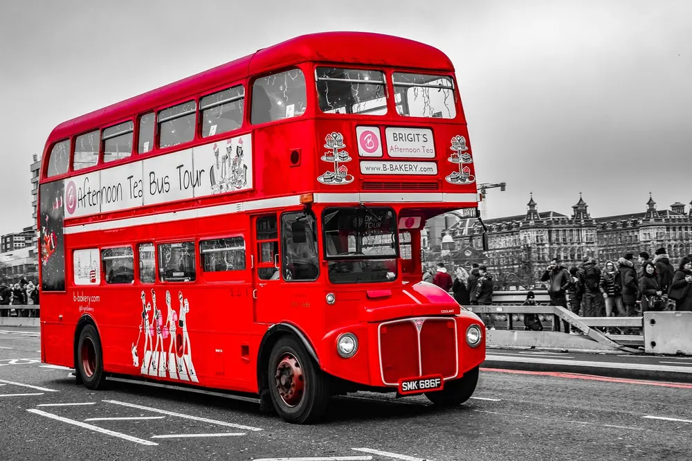Vintage red London bus touring past Westminster
